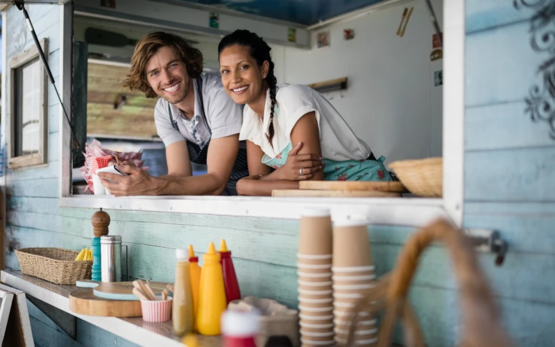 Two young business owners at the service window of their outdoor restaurant