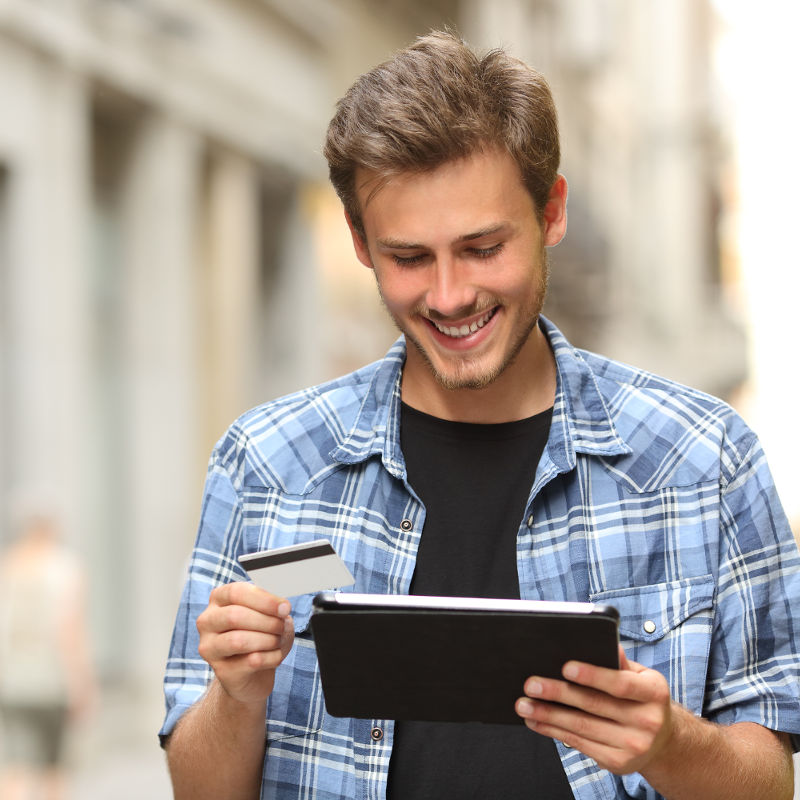 photo of young man using a credit card and tablet