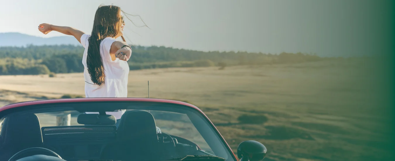 Woman in a white shirt enjoying freedom with her car in the great outdoors