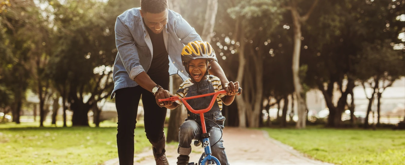 photo of a dad helping his son ride a bike